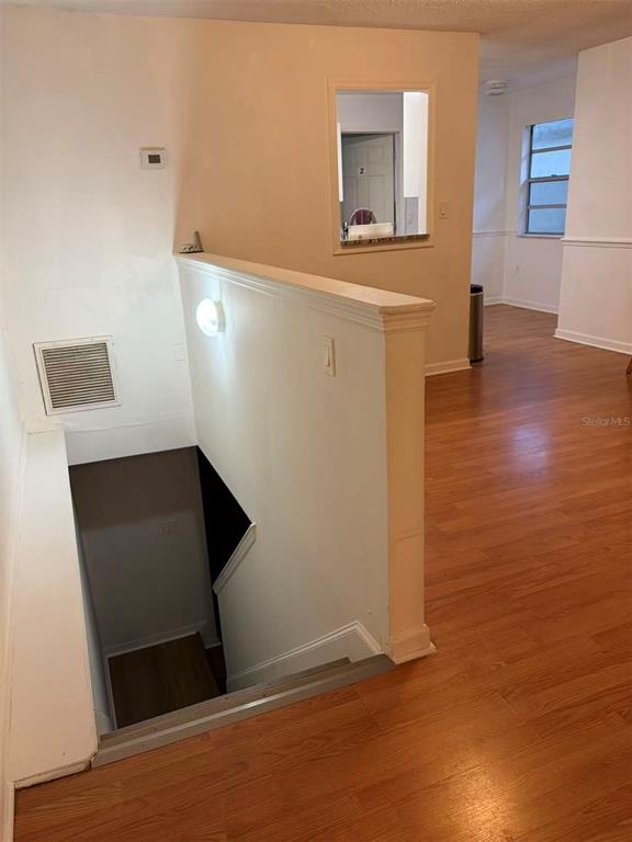 A staircase leads down from a landing with wood-look flooring and a pass-through window — 1160 WOODMAN WAY, ORLANDO, FL