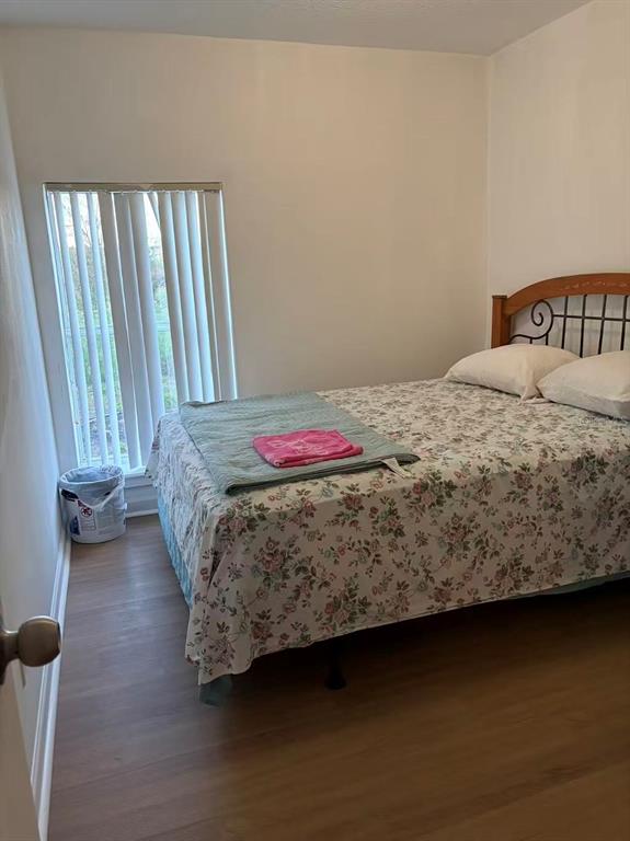 A bedroom features a floral bedspread, a wooden headboard, and vertical blinds over a window — 1160 WOODMAN WAY, ORLANDO, FL