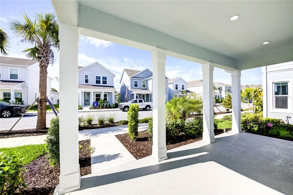A view from a covered front porch looking out toward neighboring suburban houses and landscaping — 9116 WALCOTT LANE, SARASOTA, FL
