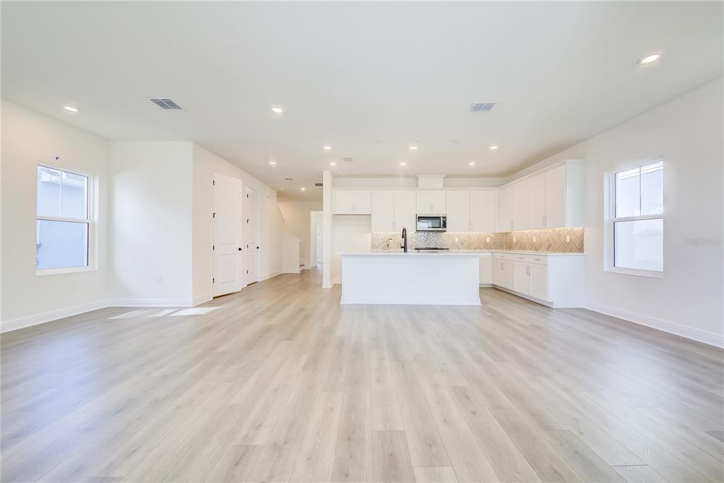 A bright, open-concept kitchen features white cabinetry, a central island, and light wood-look flooring — 9116 WALCOTT LANE, SARASOTA, FL