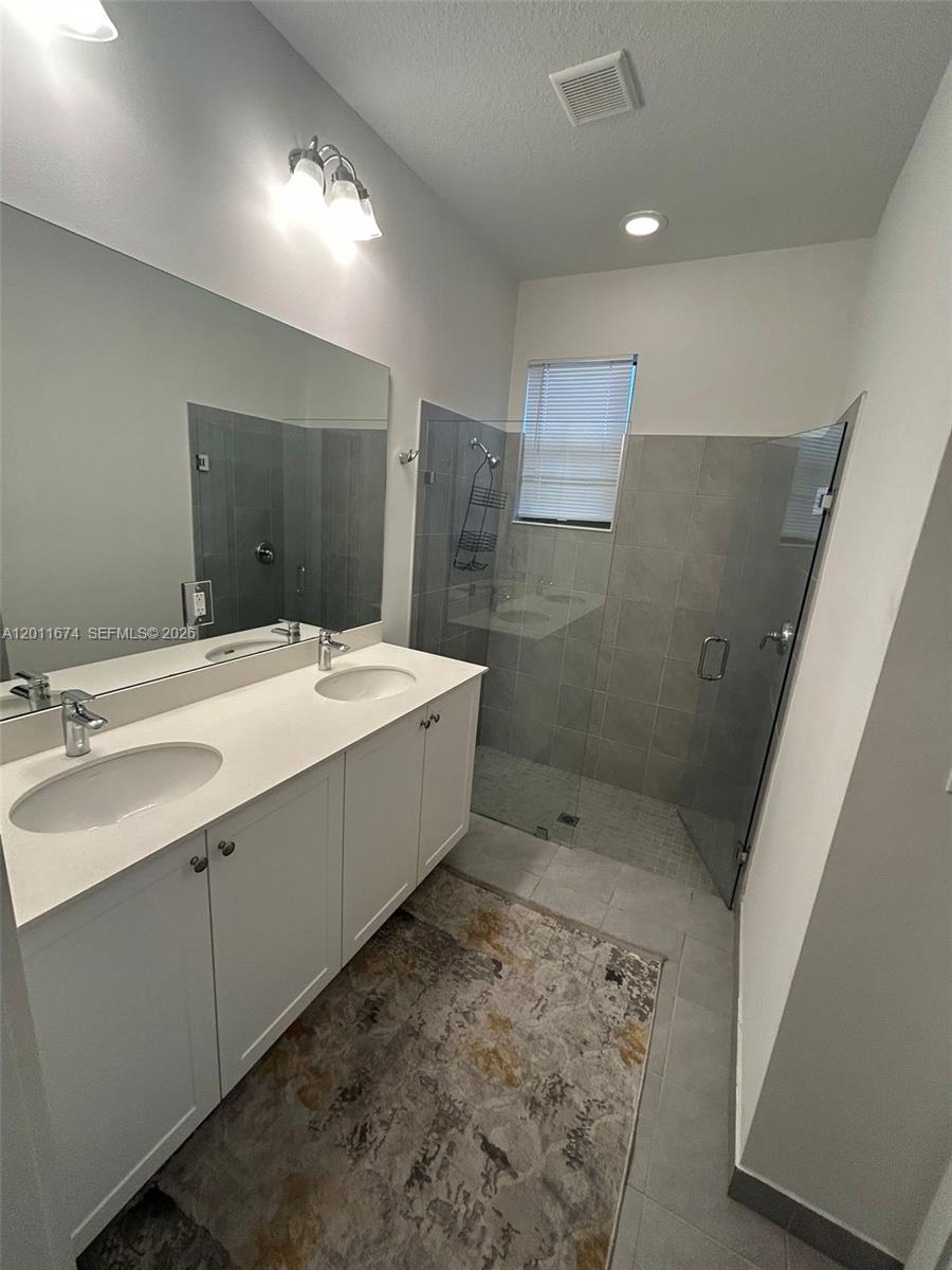 A bathroom features a double vanity with white cabinets and a walk-in glass shower — 5541 AGOSTINO WAY # 5541, Ave Maria FL 34142, AVE MARIA, FL