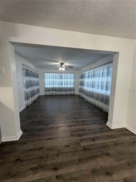 A spacious room with dark wood-look flooring, white walls, and floor-to-ceiling striped curtains — 320 S HARRISON STREET, BEVERLY HILLS, FL