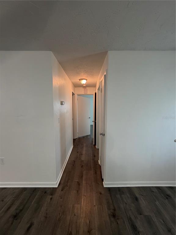 A hallway with wood-look flooring leads to a doorway under a ceiling light fixture — 320 S HARRISON STREET, BEVERLY HILLS, FL
