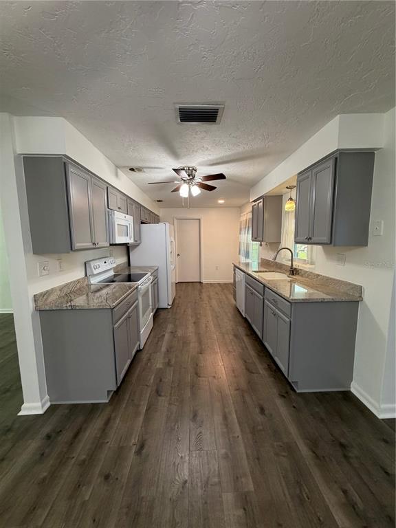 A galley kitchen features gray cabinets, granite countertops, and wood-look flooring — 320 S HARRISON STREET, BEVERLY HILLS, FL