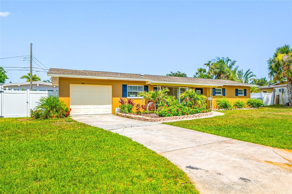 A single-story house with a yellow exterior, a garage, and a landscaped front yard — 5056 42ND STREET S, ST PETERSBURG, FL