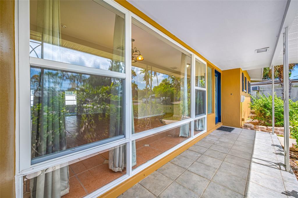 A tiled patio area features large windows looking into a room with a chandelier — 5056 42ND STREET S, ST PETERSBURG, FL