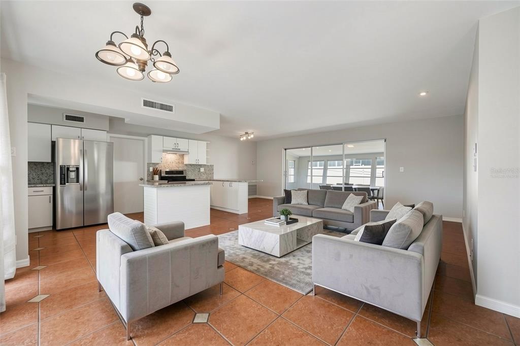 An open-concept living room and kitchen featuring tile flooring, grey furniture, and a marble table — 5056 42ND STREET S, ST PETERSBURG, FL