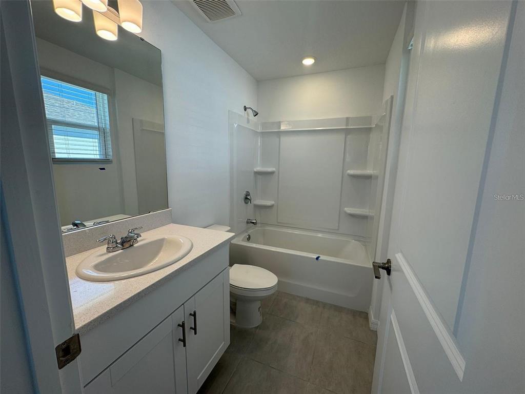 A bathroom features a white vanity with a sink, a toilet, and a tub-shower combination — 3133 SKYLINE LOOP, KISSIMMEE, FL