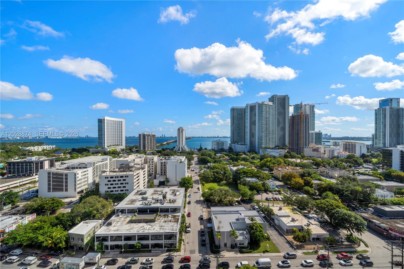 An elevated view of a city skyline with tall buildings, green trees, and a bay — 121 NE 34th St # 1704, Miami FL 33137, MIAMI, FL