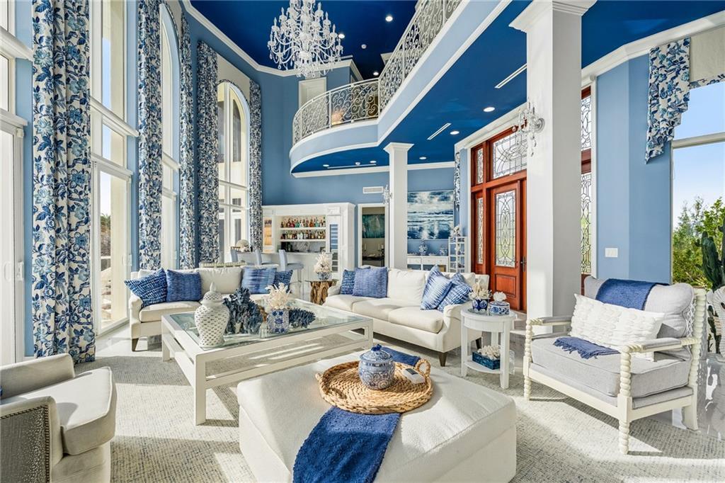 A spacious living room features blue walls, a high ceiling, a balcony, and white furniture — FORT PIERCE, FL