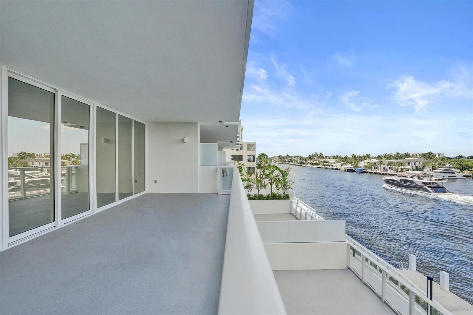 A spacious, modern balcony overlooks a canal with a passing yacht and waterfront homes — 407 N Riverside Drive # 303, Pompano Beach FL 33062, POMPANO BEACH, FL