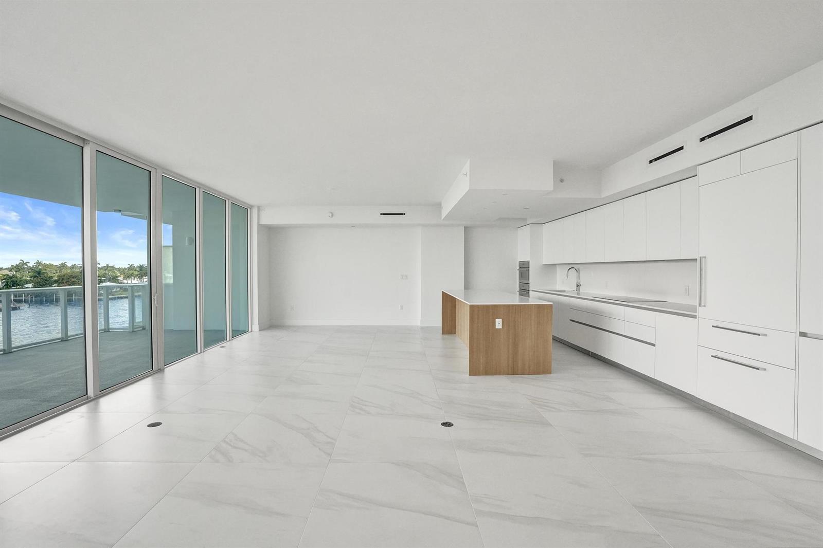 A modern, minimalist kitchen and living area with white marble floors and floor-to-ceiling windows — 407 N Riverside Drive # 303, Pompano Beach FL 33062, POMPANO BEACH, FL