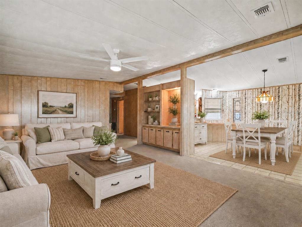 A living room and dining area feature wood-paneled walls, neutral furniture, and a built-in hutch — 134 LAKE HAZEL DRIVE, WINTER HAVEN, FL