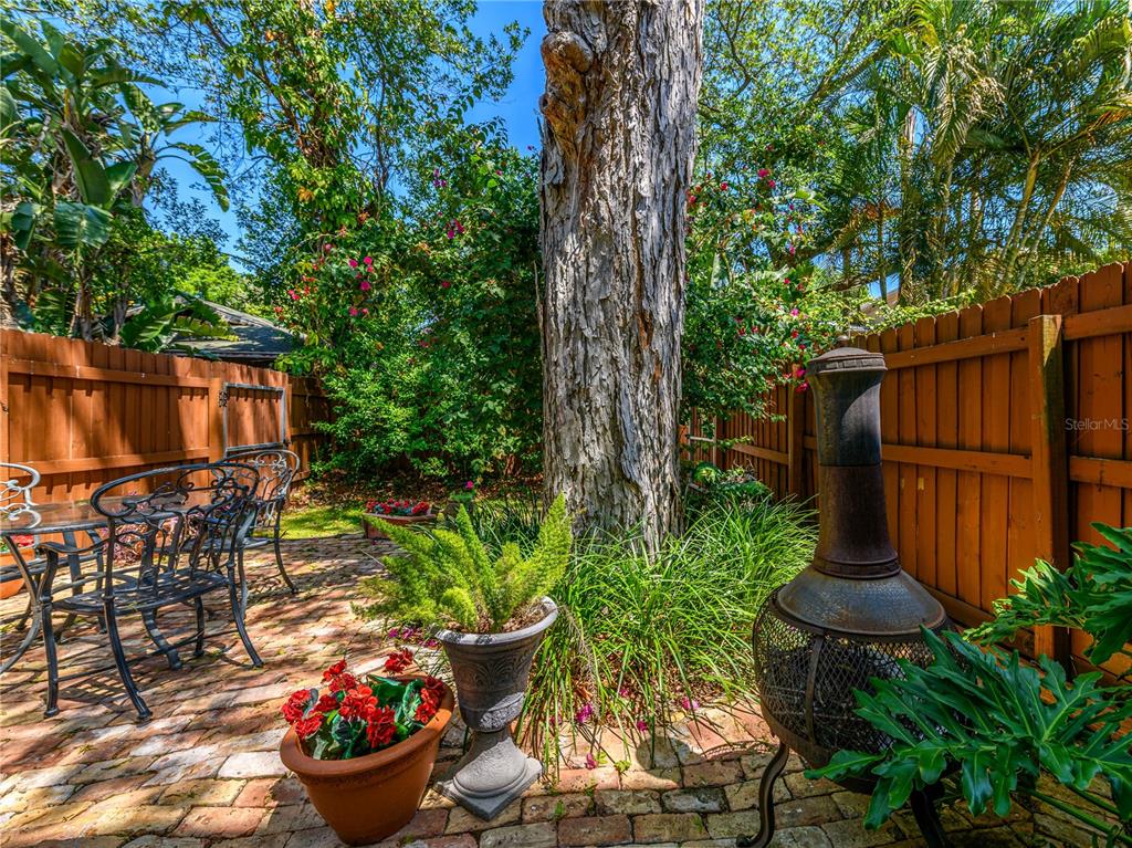 A brick patio features a metal table set, potted plants, and a chiminea near trees — 204 S LINCOLN AVENUE, TAMPA, FL