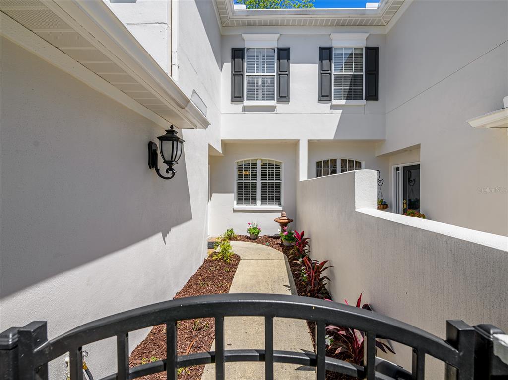 A paved walkway leads through a courtyard to the entrance of a two-story stucco home — 204 S LINCOLN AVENUE, TAMPA, FL