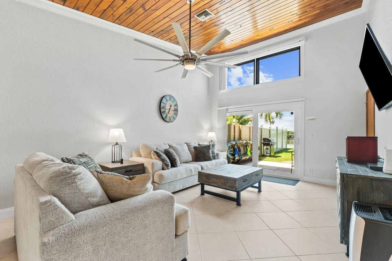 A living room features a wood-paneled vaulted ceiling, a large ceiling fan, and sliding doors — 12542 Westhampton Circle, Wellington FL 33414, WELLINGTON, FL