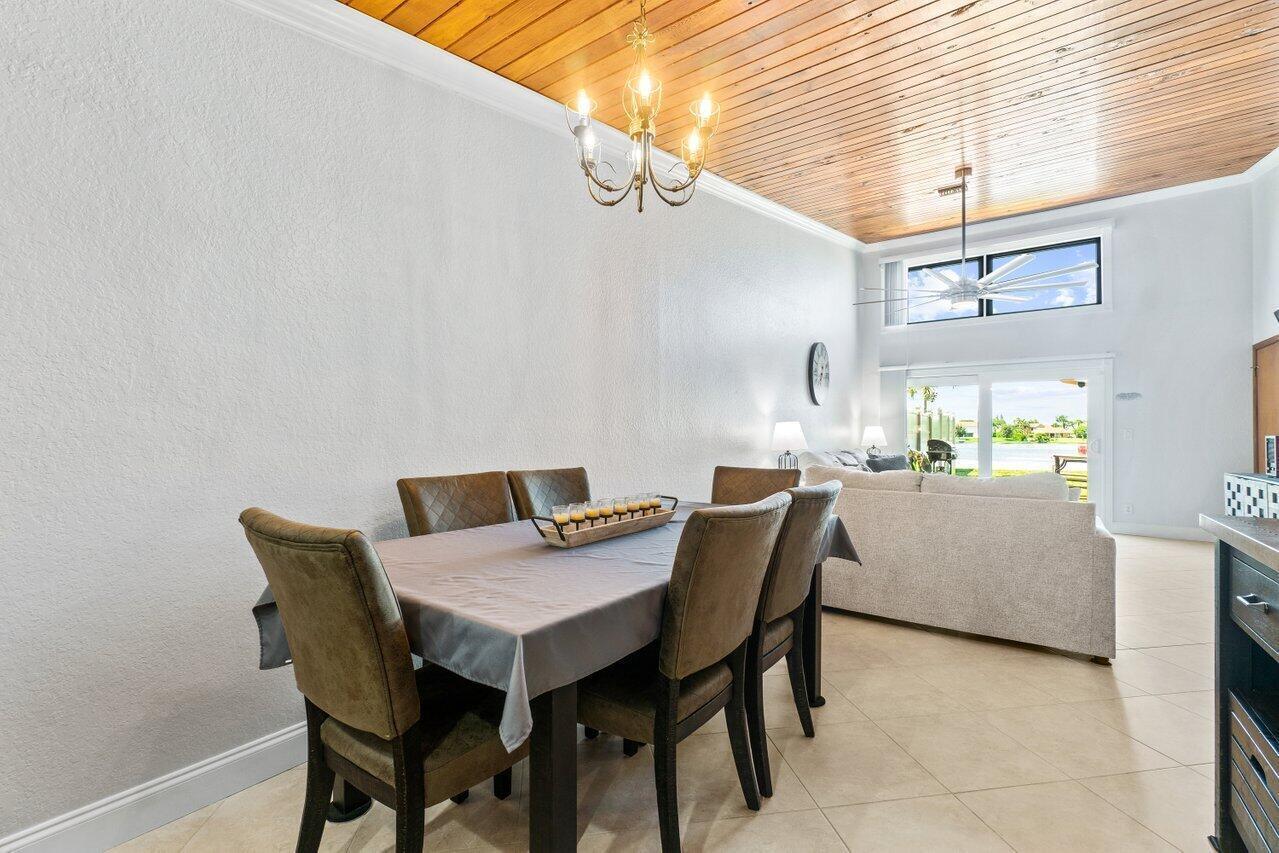 A dining area features a wooden plank ceiling, a chandelier, and tile flooring — 12542 Westhampton Circle, Wellington FL 33414, WELLINGTON, FL