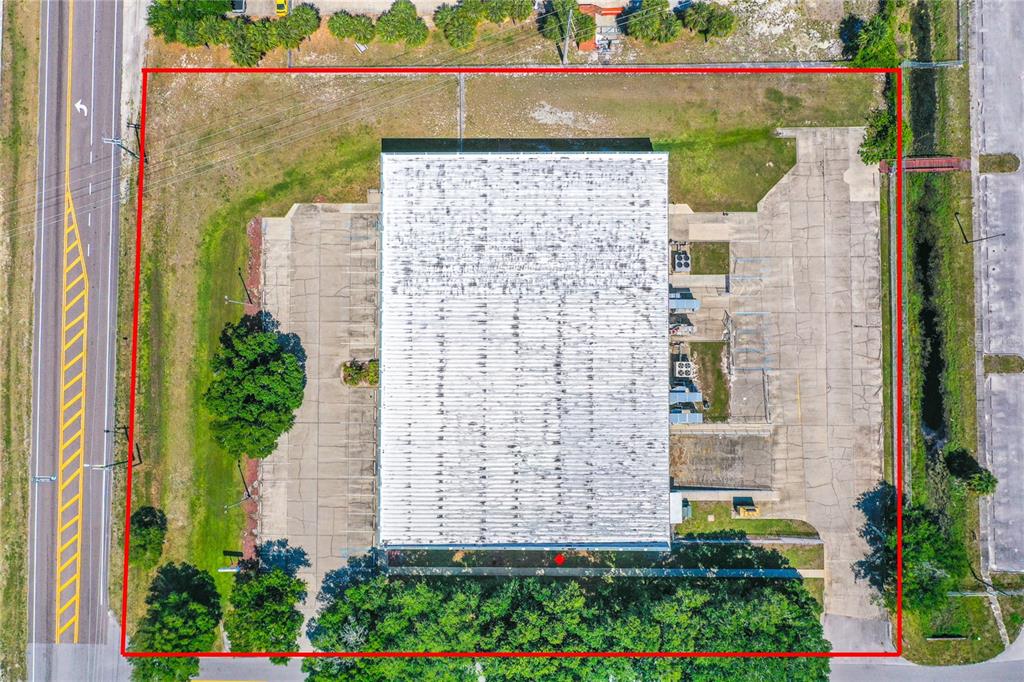 An aerial view shows a rectangular commercial building surrounded by parking lots and green space — 295 BARNES BOULEVARD, ROCKLEDGE, FL