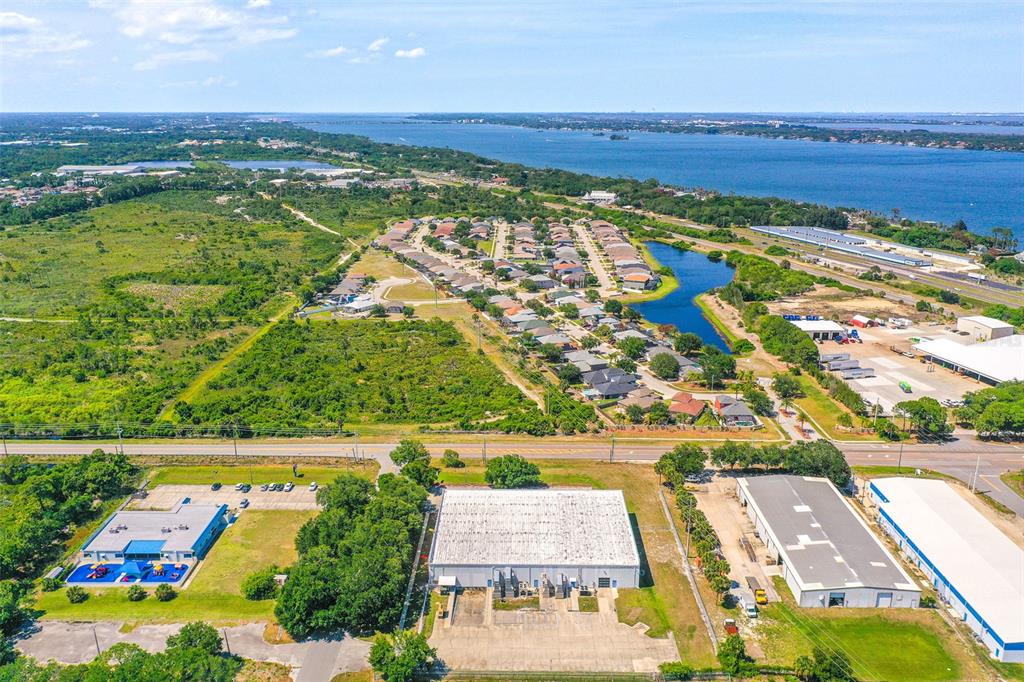An aerial view shows industrial buildings, a residential neighborhood, and a large body of water — 295 BARNES BOULEVARD, ROCKLEDGE, FL