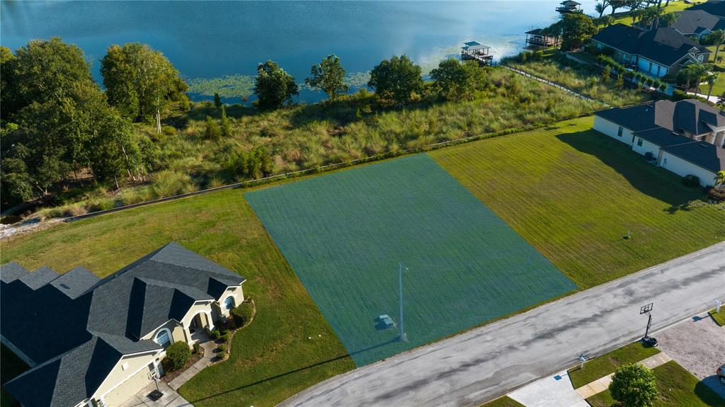 An aerial view shows a vacant residential lot highlighted in green next to a house — 7376 BENT GRASS DRIVE, WINTER HAVEN, FL