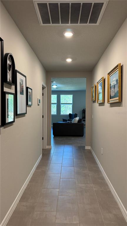 A tiled hallway leads toward a living room with windows and a dark sofa — 17268 CAGAN CROSSINGS BOULEVARD, CLERMONT, FL