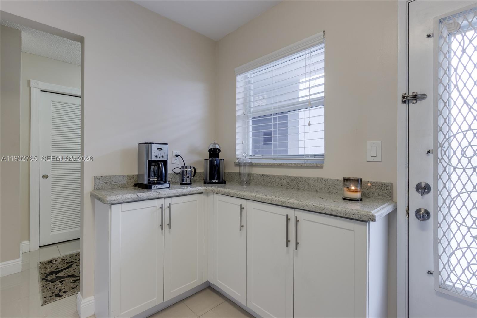 A kitchen corner features white cabinets, granite countertops, a window, and a coffee station — 420 NE 12th Ave # 208, Hallandale Beach FL 33009, HALLANDALE BEACH, FL