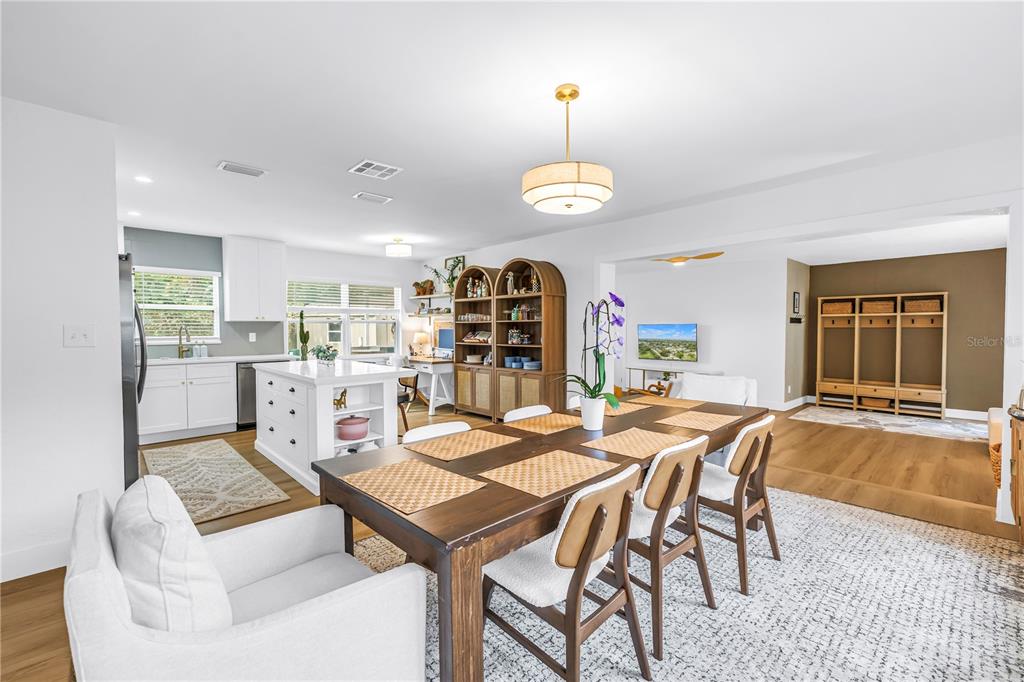 A dining area with a wooden table and chairs sits adjacent to a white kitchen — 7400 19TH AVENUE N, ST PETERSBURG, FL
