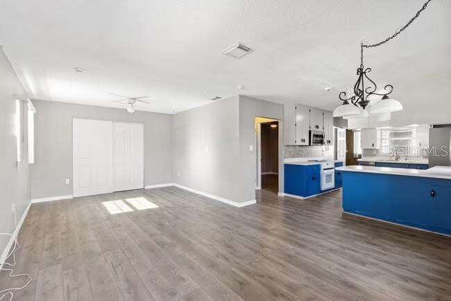 A living room with wood-look flooring opens to a kitchen with blue cabinets — 5318 17TH STREET W UNIT A, BRADENTON, FL