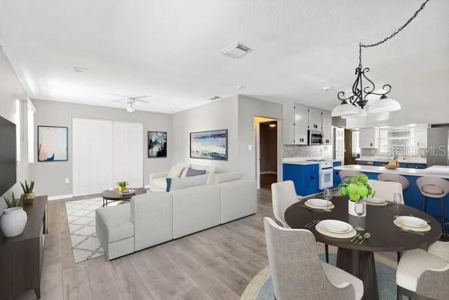 An open-concept living room and kitchen featuring light wood flooring and a round dining table — 5318 17TH STREET W UNIT A, BRADENTON, FL