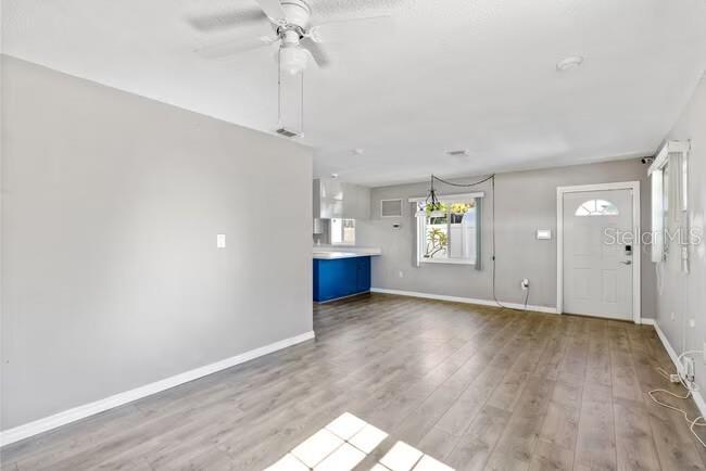 An open-concept living area features light gray walls, wood-look flooring, and a blue kitchen island — 5318 17TH STREET W UNIT A, BRADENTON, FL