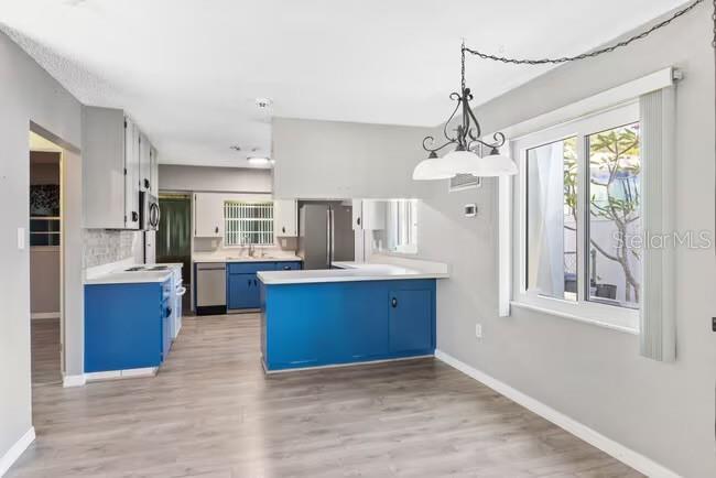 A kitchen and dining area with blue lower cabinets, grey upper cabinets, and wood-look flooring — 5318 17TH STREET W UNIT A, BRADENTON, FL