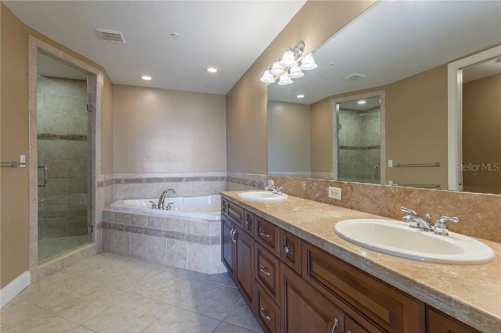 A bathroom features a soaking tub, a glass-enclosed shower, and a double vanity with mirrors — 1714 PARK STREET N, ST PETERSBURG, FL