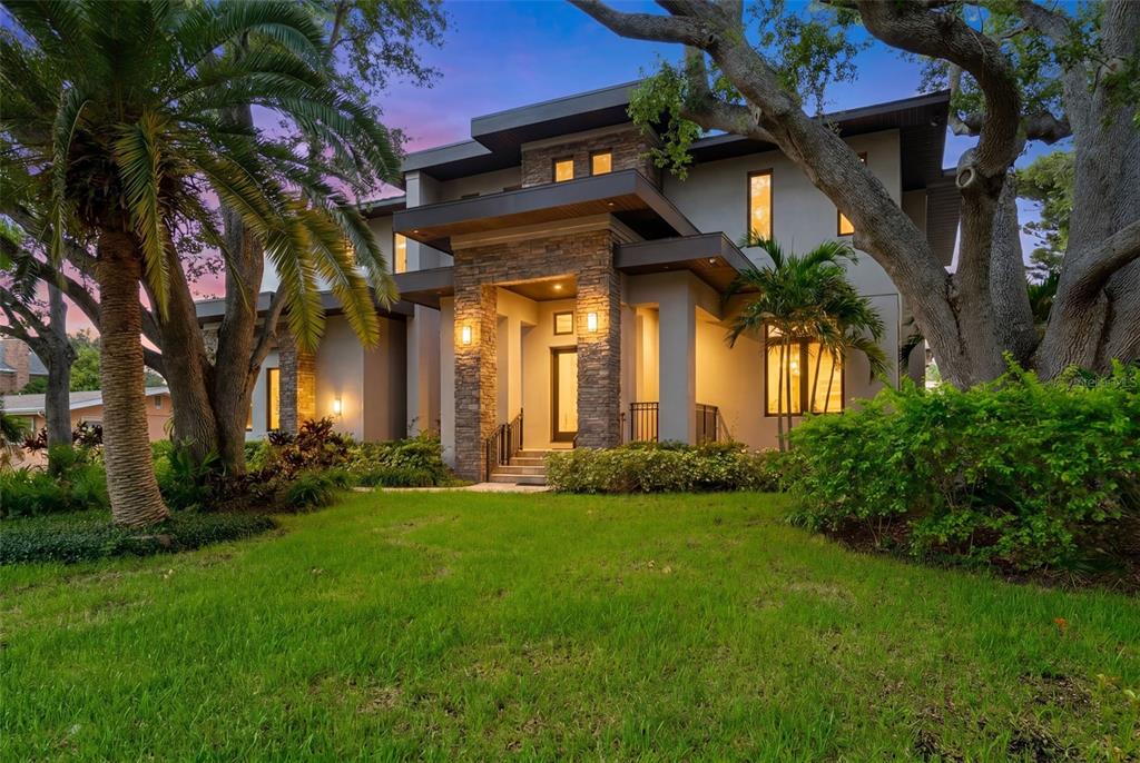 A modern two-story house with stone accents and a palm-lined lawn at twilight — 4905 W SPRING LAKE DRIVE, TAMPA, FL