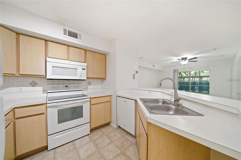 A kitchen with light wood cabinets, white appliances, white countertops, and a double sink — 823 CAMARGO WAY UNIT 104, ALTAMONTE SPRINGS, FL