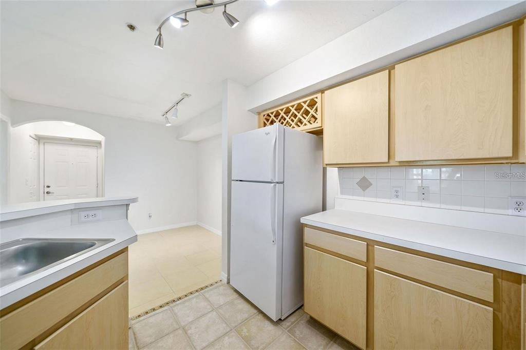 A kitchen features light wood cabinets, white countertops, a white refrigerator, and tiled flooring — 823 CAMARGO WAY UNIT 104, ALTAMONTE SPRINGS, FL
