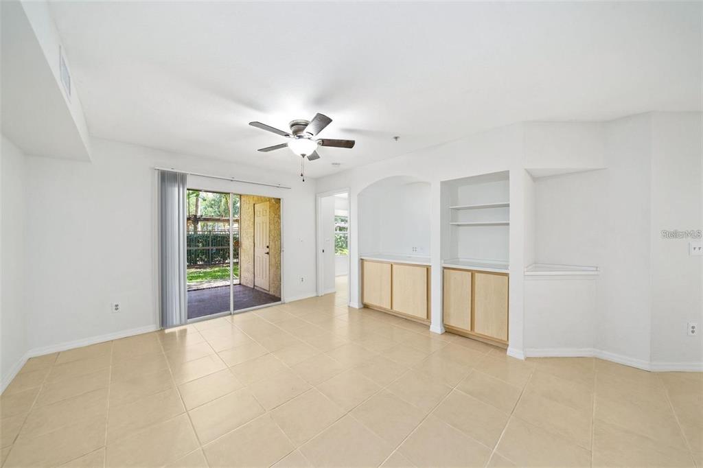 A bright room with beige tile flooring, a ceiling fan, built-in cabinets, and sliding glass doors — 823 CAMARGO WAY UNIT 104, ALTAMONTE SPRINGS, FL