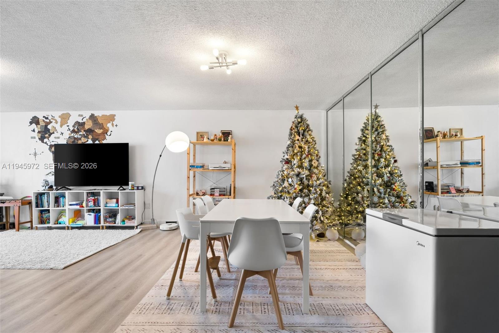 A dining area features a white table, modern chairs, a Christmas tree, and mirrored closet doors — 600 Three Islands Blvd # 606, Hallandale Beach FL 33009, HALLANDALE BEACH, FL