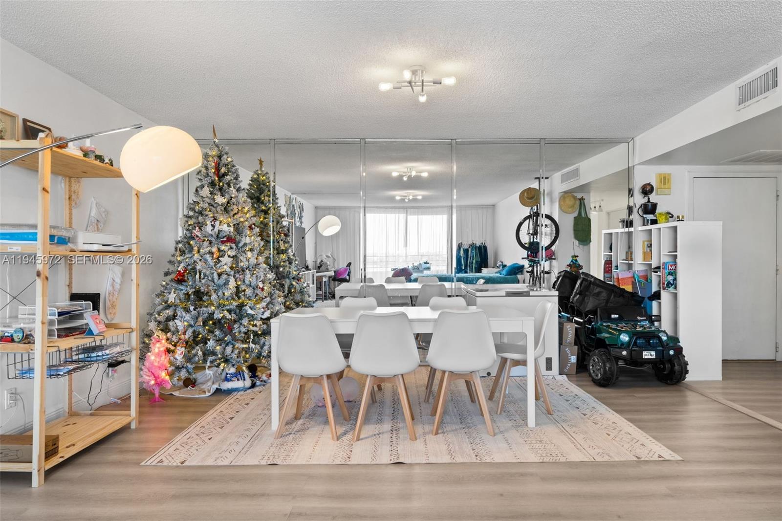 A dining area features a white table, four chairs, a Christmas tree, and mirrored walls — 600 Three Islands Blvd # 606, Hallandale Beach FL 33009, HALLANDALE BEACH, FL