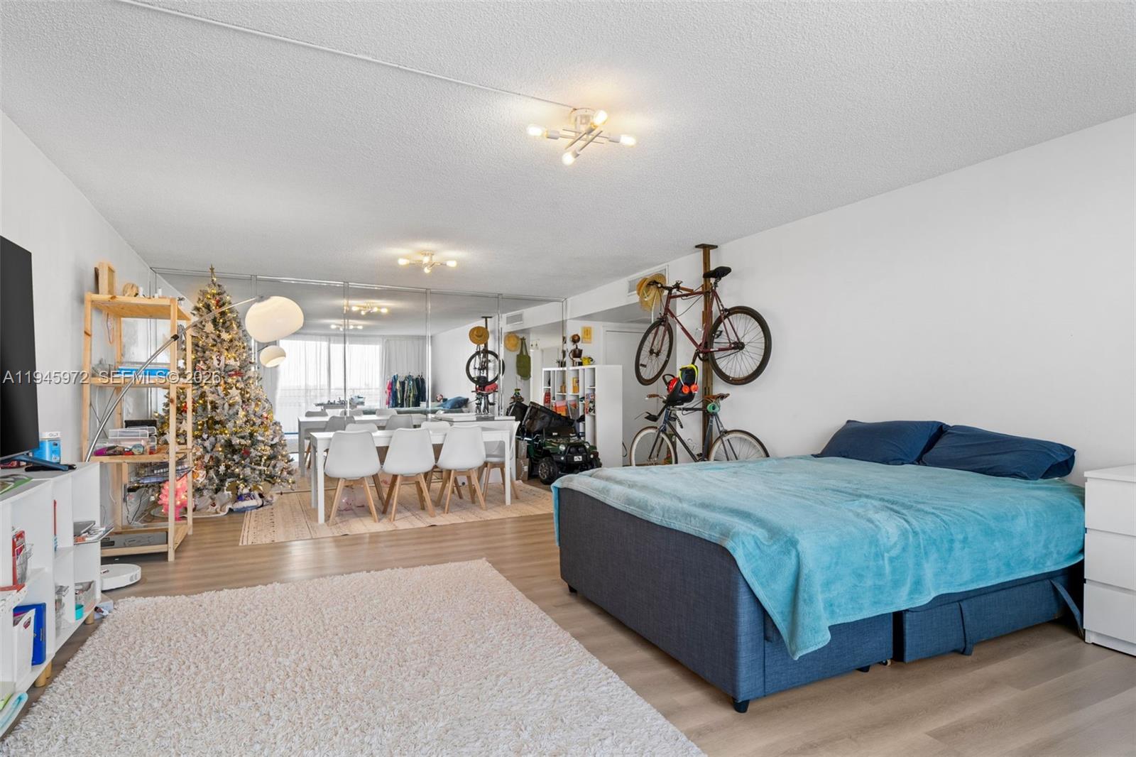 A studio apartment features a bed, dining area, Christmas tree, and wall-mounted bicycles — 600 Three Islands Blvd # 606, Hallandale Beach FL 33009, HALLANDALE BEACH, FL