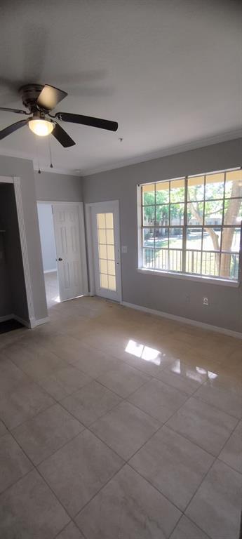 A room with light-colored tile flooring, a ceiling fan, a glass-paneled door, and large windows — 2544 ROBERT TRENT DRIVE UNIT 825, ORLANDO, FL