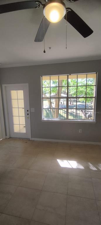 A room with light-colored tile flooring, a ceiling fan, a glass-paneled door, and a large window — 2544 ROBERT TRENT DRIVE UNIT 825, ORLANDO, FL