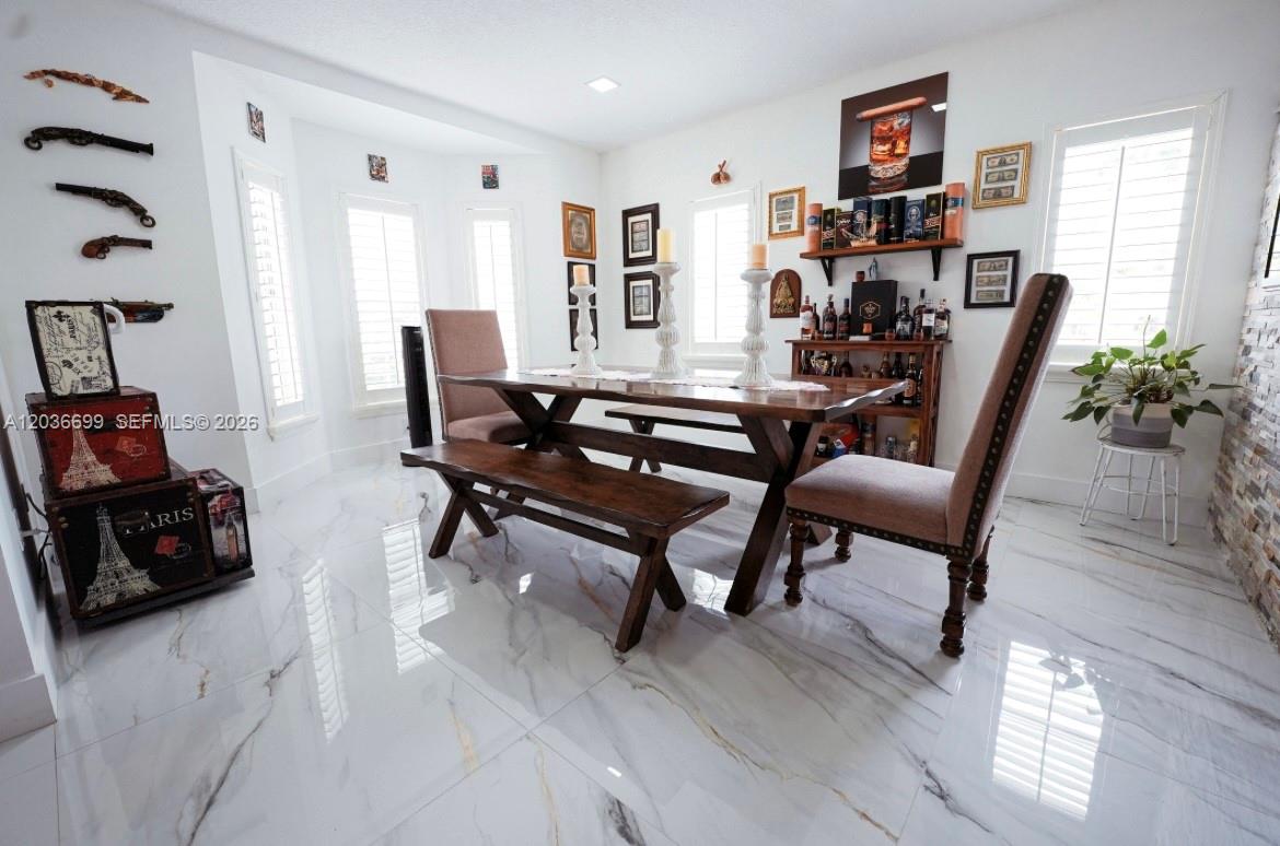 A dining room features a wooden table, bench, chairs, and marble-look tile flooring — 1935 NE 35th Ave, Homestead FL 33033, HOMESTEAD, FL