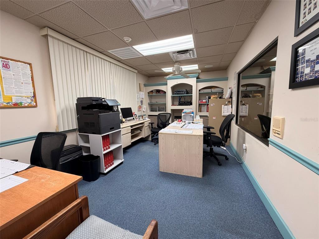 An office space features a central desk, a printer station, built-in shelving, and blue carpeting — 13610 LEARNING COURT, FORT MYERS, FL