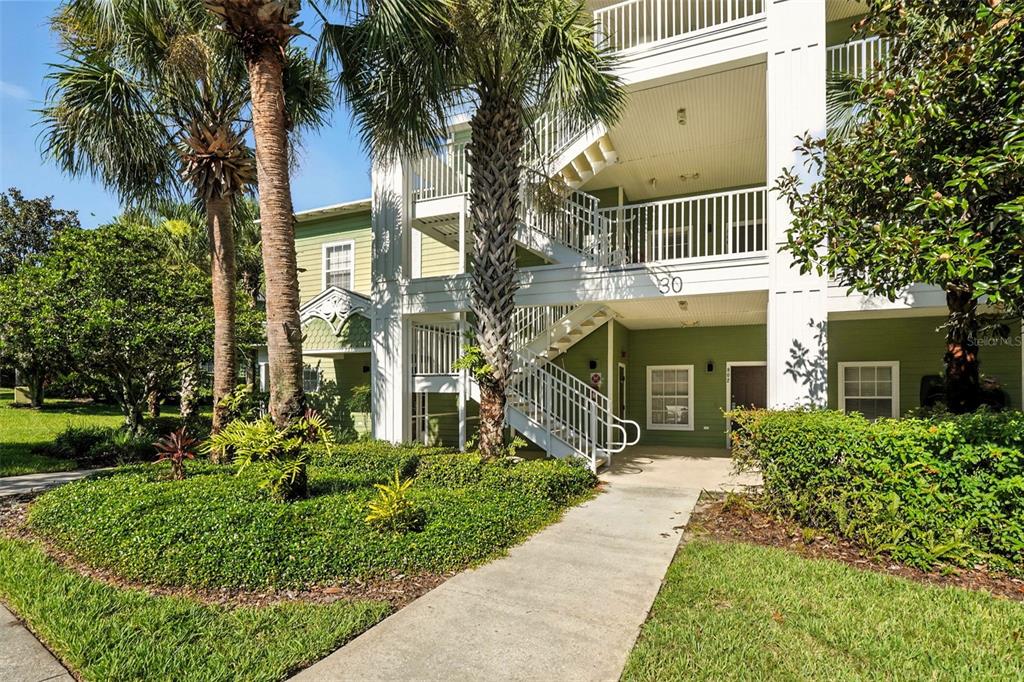 A multi-story apartment building exterior features white railings, green siding, and a concrete walkway — 809 GRAN BAHAMA BOULEVARD UNIT 30809, DAVENPORT, FL