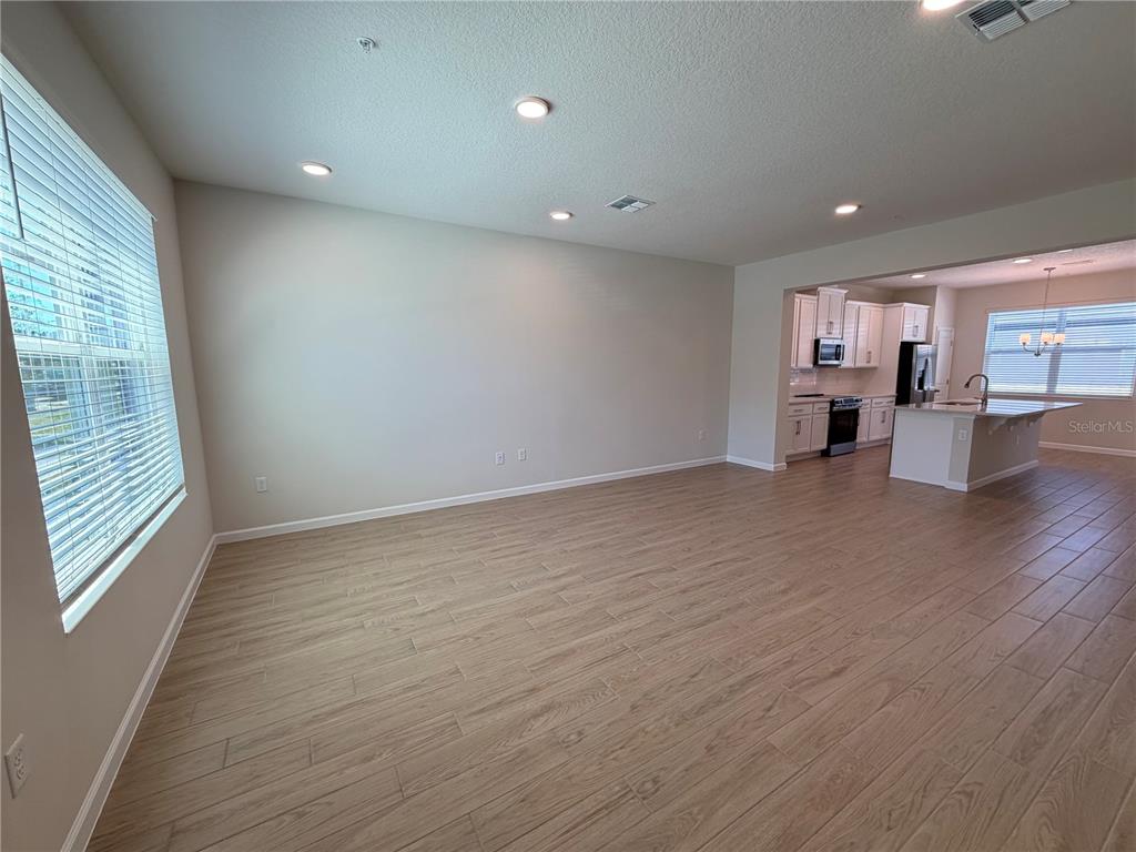 An open-concept living area features light wood-look tile flooring and a view into the kitchen — 474 LADY PALM STREET, APOPKA, FL