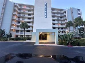 The exterior of a multi-story apartment building labeled East Tower features a covered entrance — 300 WOODETTE DRIVE UNIT 303, DUNEDIN, FL