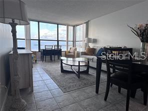 A living room features a white sofa, accent chairs, a glass coffee table, and large windows — 300 WOODETTE DRIVE UNIT 303, DUNEDIN, FL