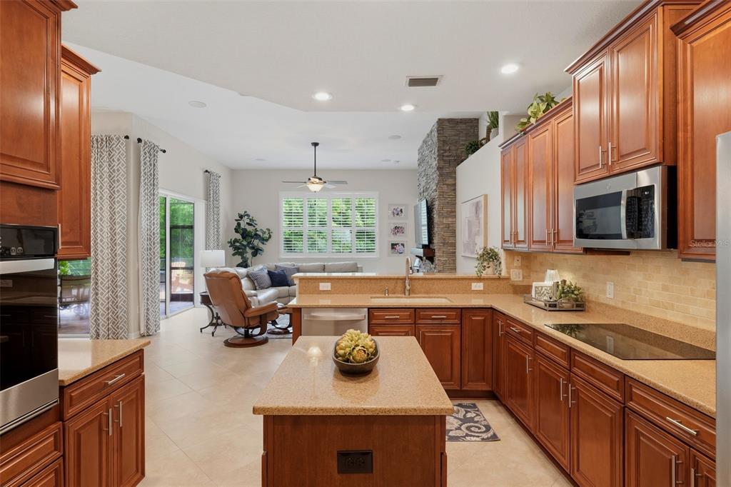 A kitchen with wood cabinets and granite countertops opens to a living room with tile — 14828 MAN O WAR DRIVE, ODESSA, FL