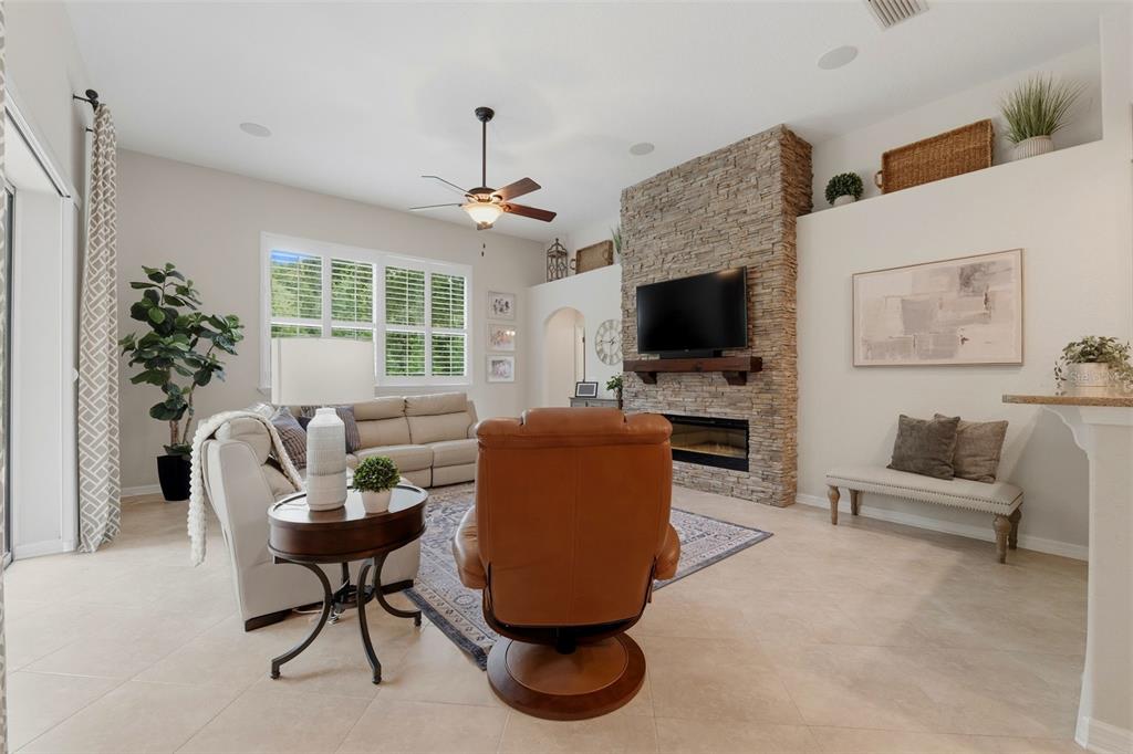 A living room features a stone fireplace, a television, a leather recliner, and neutral furniture — 14828 MAN O WAR DRIVE, ODESSA, FL