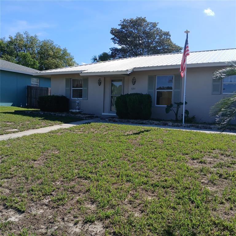 A single-story house with a white metal roof, beige siding, and a front yard — 9201 N CARESSA WAY, CITRUS SPRINGS, FL